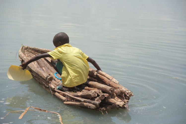 A boy wades through the crocodile-infested Lake Baringo to attend learning at Kokwa Primary School