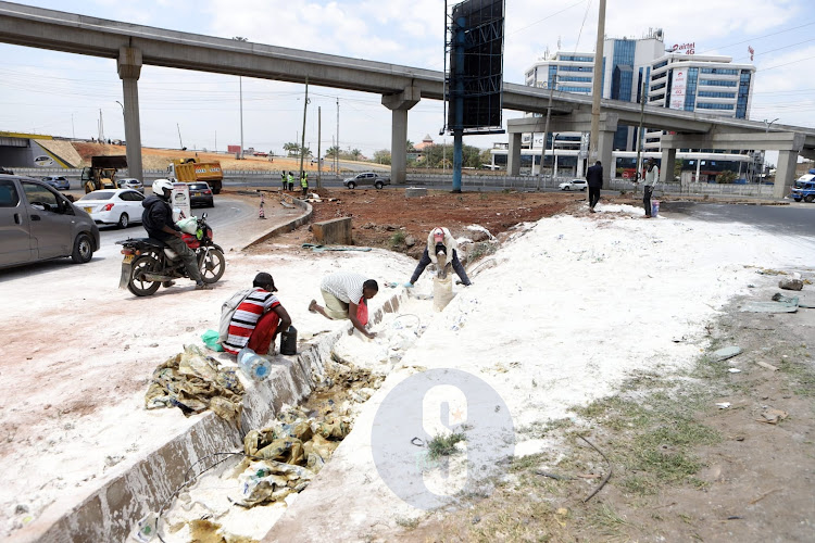 People collect unga after a lorry overturned along Mombasa Road, Nairobi on September 23, 2022.