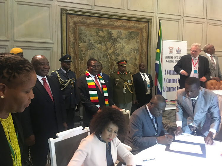 Cyril Ramaphosa and Emmerson Mnangagwa look on as ministers Lindiwe Sisulu and Perence Shiri sign on behalf of their countries in Harare on Tuesday.