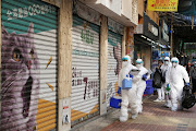 Officers in protective suits walk outside a closed pet shop in Mong Kok district after a hamster cull was ordered to curb the Covid-19 outbreak in Hong Kong, China.