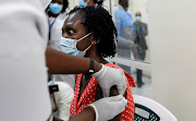 A woman reacts as she receives the AstraZeneca/Oxford vaccine under the COVAX scheme against coronavirus disease (Covid-19) at the Kenyatta National Hospital in Nairobi, Kenya March 5, 2021. 