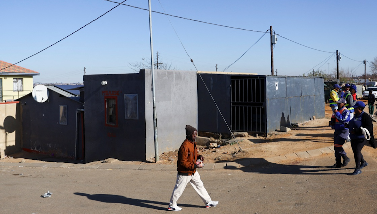 A man walks past the scene where15 people were killed in a hail of at least 137 bullets by unknown gunmen inside a tavern in Nomzamo informal settlement in Soweto.