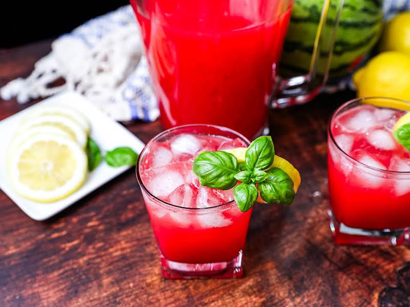 Garnish A Glass Of Basil-infused Watermelon Lemonade With Basil And A Lemon Slice.