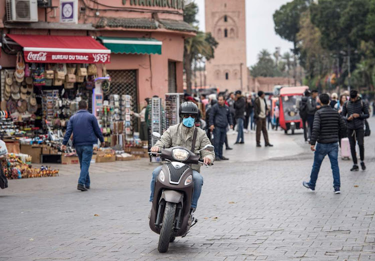 A man wearing a protective mask rides his scooter at Marrakesh's Jamaa el-Fna square. - Many holiday makers who came to visit Morocco are now finding themselves confined as the government is gradually restricting all activities in the kingdom and closing down universities, schools, cinemas, museums, bars, restaurants and even mosques, all in a bid to stem the spread of Covid-19 coronavirus.
