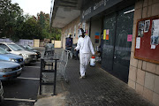 A man disinfects a shopping trolley outside a grocer in Johannesburg on April 3 2020.  