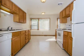 Gallery style kitchen with tile flooring and overhead lighting next to the dining area with a large window