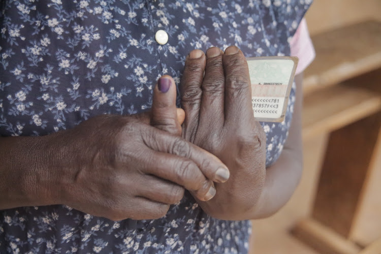 An elderly woman displays her marked finger after successfully voting at Kapsoo polling station, Baringo Central, on Tuesday.