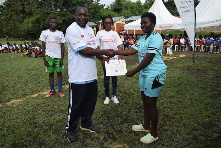 Homa Bay urban zone curriculum supports director Jacob Dola handover certificate to student Stermily Odhiambo in Homa Bay town on April 13,2024