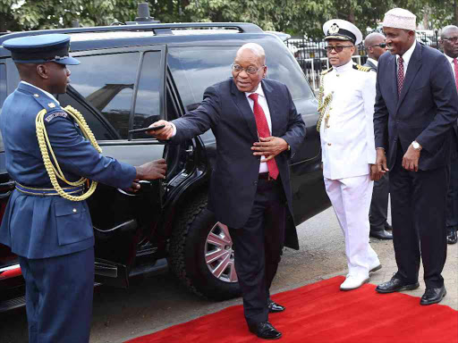 South African President Jacob Juma hands over his mobile phone to his aide before he laid a wreath at the Jomo Kenyatta Mausoleum in Parliament on Tuesday.Photo/HEZRON NJOROGE