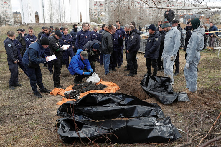 French forensics investigators, who arrived to Ukraine for the investigation war crimes amid Russia's invasion, watch as Ukrainian colleagues explore remains of bodies of burned civilians exhumed from a grave in the town of Bucha, Ukraine on April 13, 2022. Picture: REUTERS/VALENTYN OGIRENKO