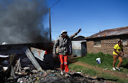 A local gestures after the burning of shacks and belongings as they searched for alleged illegal miners known as ‘zama-zamas’ as a protest, following alleged rape of eight models on July 28 when a television crew filmed a music video at a mine dump in the nearby township, in the West Rand, South Africa, August 8, 2022. 