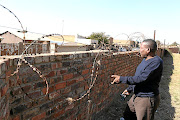 Highlands Park director Sinky Mnisi showing the short wall around Makhulong Stadium. The perimeter wall around the stadium is so low it is easy for fans to scale during high risk matches.

