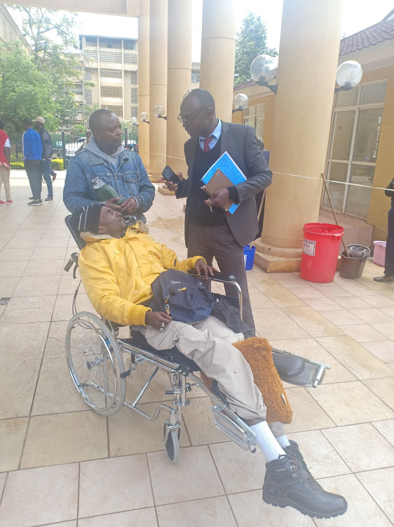 Harrison Njuguna (in a wheelchair) with lawyer Fredrick Musungu at the Milimani law courts.