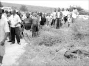 UNBELIEVABLE: Residents crowd around the body of Soshangana High School teacher Elone Sibuyi, who was shot dead by guards after a robbery at the petrol station yesterday. Pic. Roit Hlatshwayo. 18/12/2006. © Sowetan.