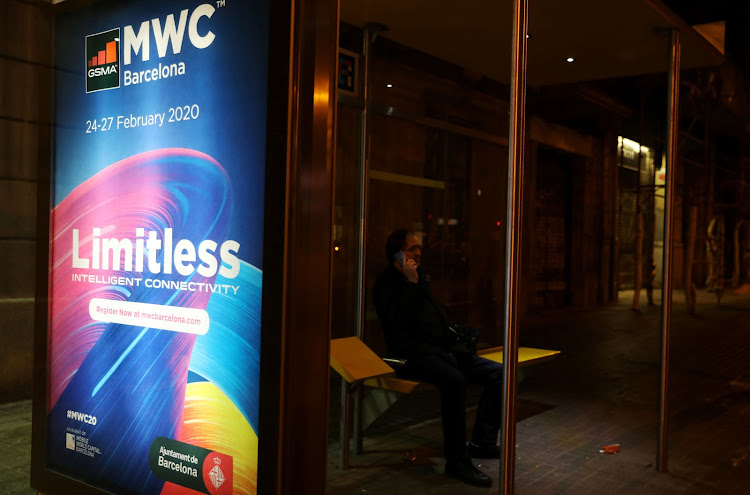 A banner of MWC20 (Mobile World Congress) is pictured as a man talks on his mobile phone at a bus stop along a street in Barcelona, Spain on February 12, 2020.