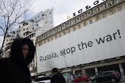 A man passes in front of a billboard against the war as Russia's attack on Ukraine continues, in Bucharest, Romania, March 14, 2022. 