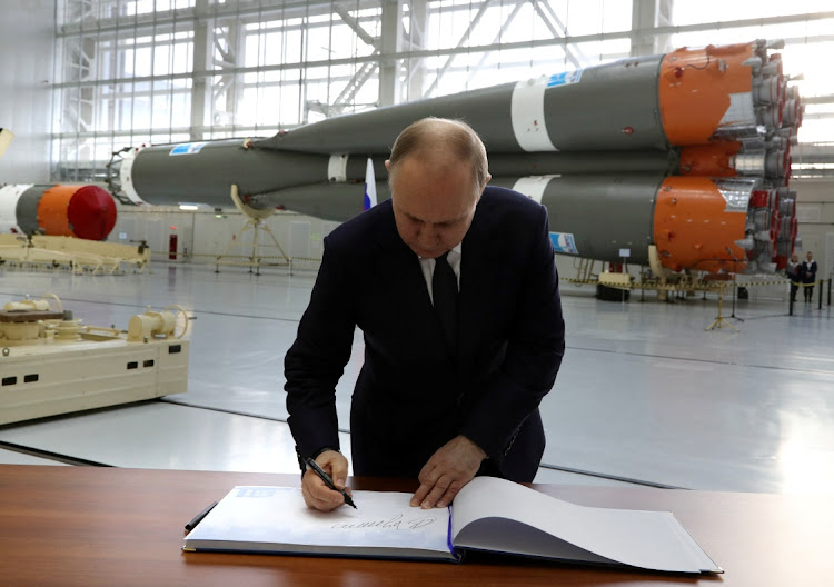 Russian President Vladimir Putin signs the distinguished visitors' book in an assembly and test facility at the Vostochny Cosmodrome in Amur Region, Russia, on April 12 2022. Picture: KREMLIN via REUTERS/SPUTNIK/MIKHAIL KLIMENTYEV