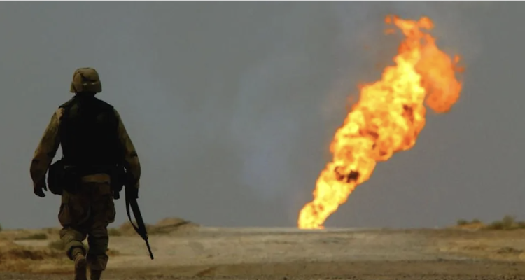 A US soldier walks towards a burning oil well in southern Iraq