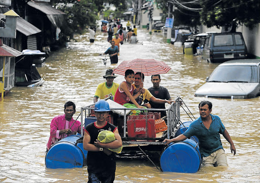 EMERGENCY EVACUATION: Filipino typhoon victims ride on a makeshift raft down a flooded street in Cabanatuan city in northern Manila, Philippines yesterday after Typhoon Koppu triggered flash floods and landslides in the northern Philippines, killing at least four people and forcing thousands of people to flee their homes. Two people drowned, one was electrocuted and a 14-year-old boy was hit by a falling tree Picture: EPA