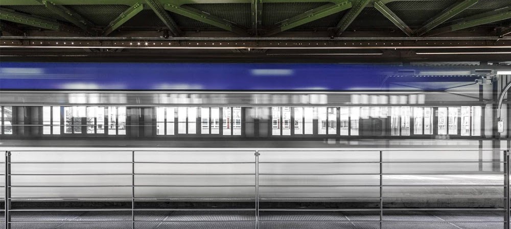 Photograph of a blue and white train in motion inside a train station