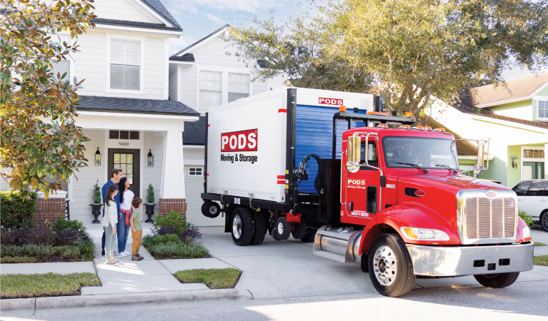 A family of four watches as their PODS portable moving container is delivered to their driveway in Colorado Springs.