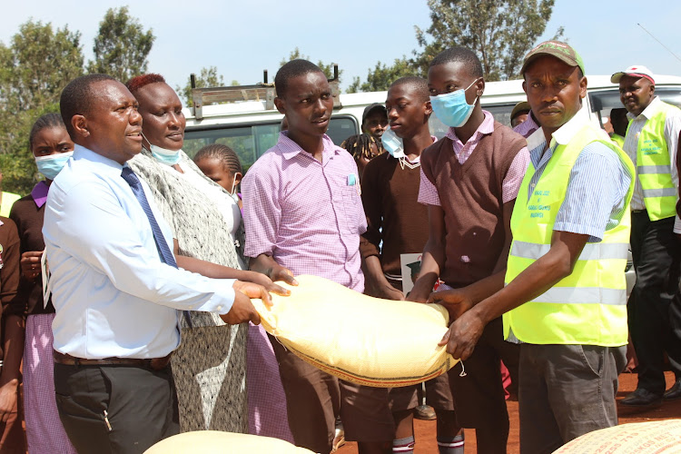 Karanja Mburu hands over rice to Githuguya Primary School pupils and management on Monday.