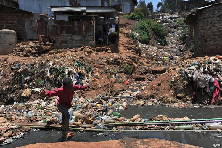 A child jumps over a sewer line in Kibra slum