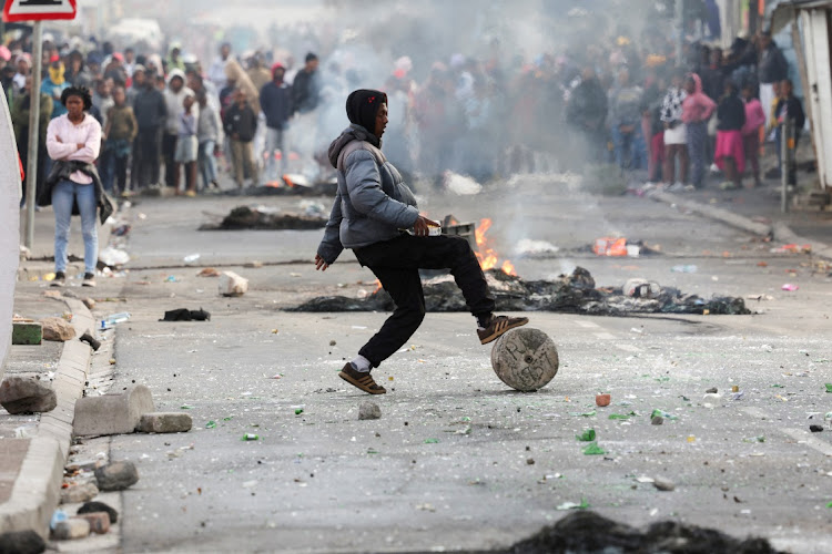 A protester blocks the street with stones and rubble during the strike by taxi operators against traffic authorities in Masiphumelele on August 8, 2023