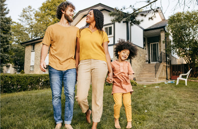 Two parents and a child smiling in the front yard with their Toronto house behind them. They are a mixed-race family, representing Toronto’s impressive diversity.