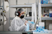 An employee gathers protective face masks from a production line conveyor at the KB MEDICA plant in Sartrouville, near Paris on October 28 2020.