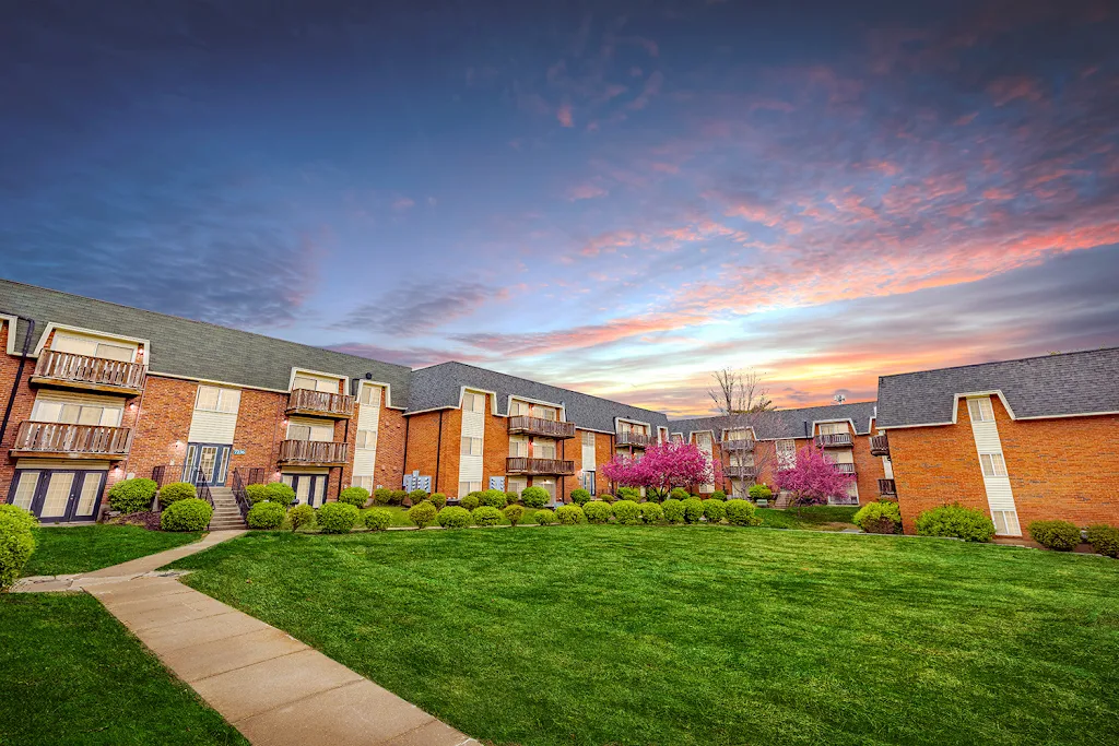 Norwood Court's apartment buildings at dusk with red brick exterior, landscaping surrounding, and grassy areas