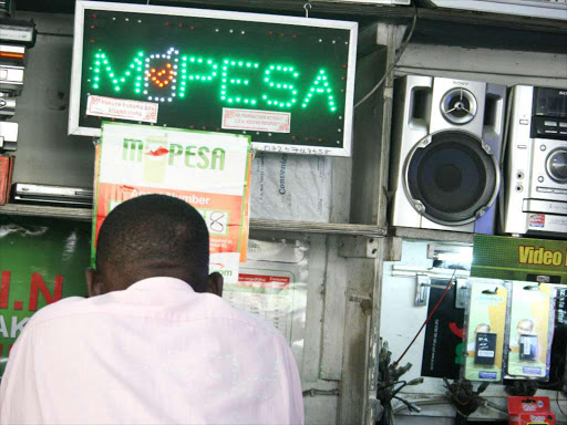 A customer waits to be served at an M-Pesa shop. /FILE