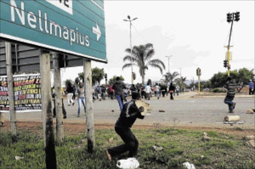 HEAVY ARMOUR: A resident carries a heavy piece of concrete to add to the barriers residents have placed on the streets as they marched towards ward councillor Precious Marole's house in Nellmapius, PretoriaPHOTO: THULANI MBELE