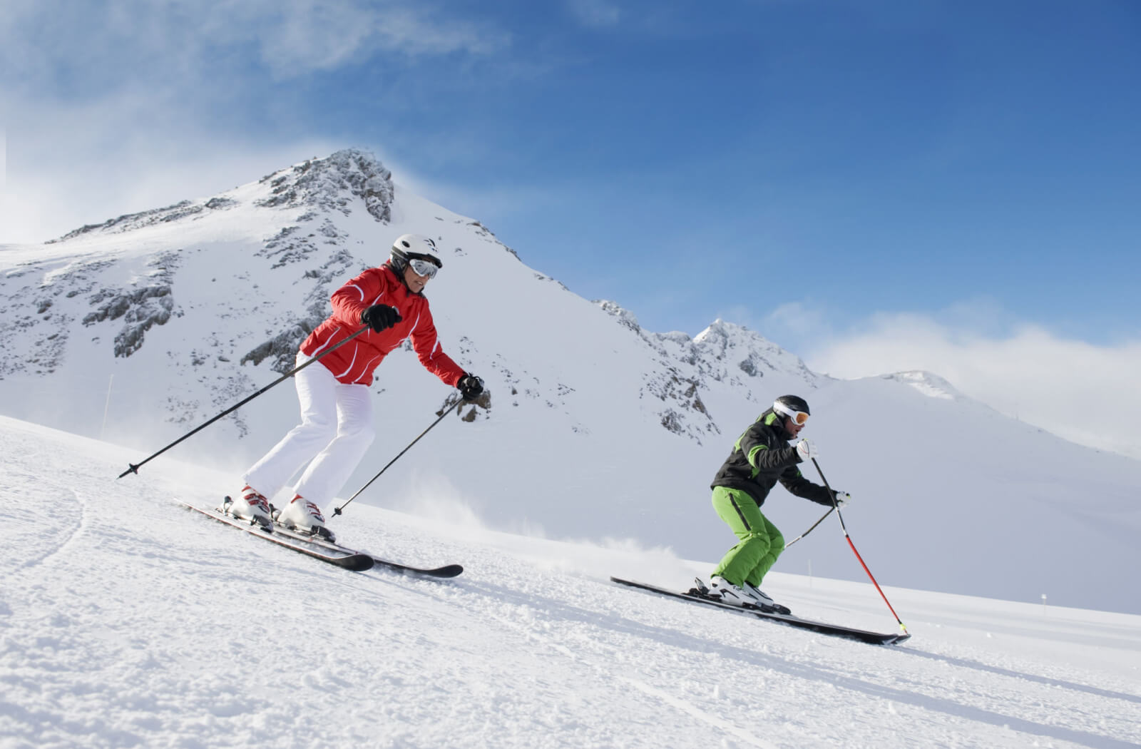 Two people skiing on a snowy mountain. One of many activities where wearing multifocal contacts be convenient.