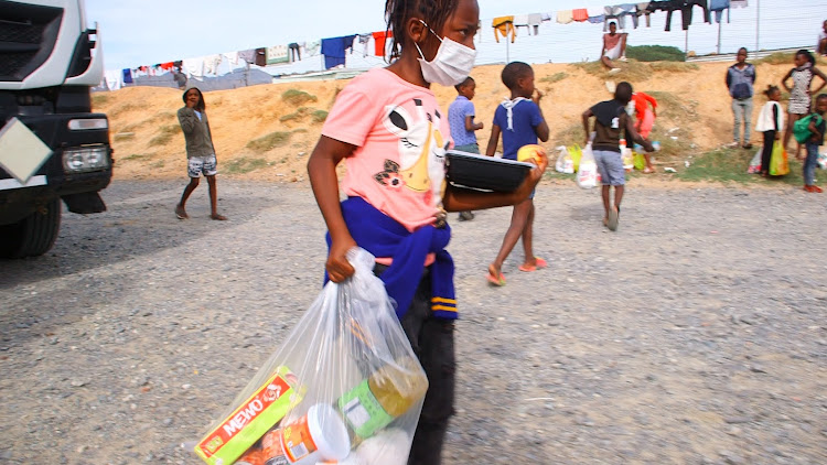 A Nomzamo primary school learner carries a food parcel donated by Gift of the Givers on May 7 2020 during the Covid-19 lockdown.