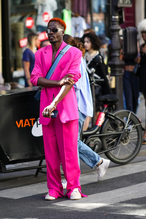 A guest wearing a neon pink blazer jacket and suit pants with beige matte leather velcro sneakers outside Jean-Paul Gaultier during Paris Fashion Week - Haute Couture Fall Winter 2022 2023.