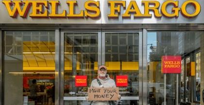 A person holding a sign in front of a store

Description automatically generated with medium confidence