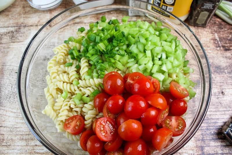 Cooked Pasta, Chopped Green Onions, Diced Celery, And Halved Cherry Tomatoes In A Bowl.