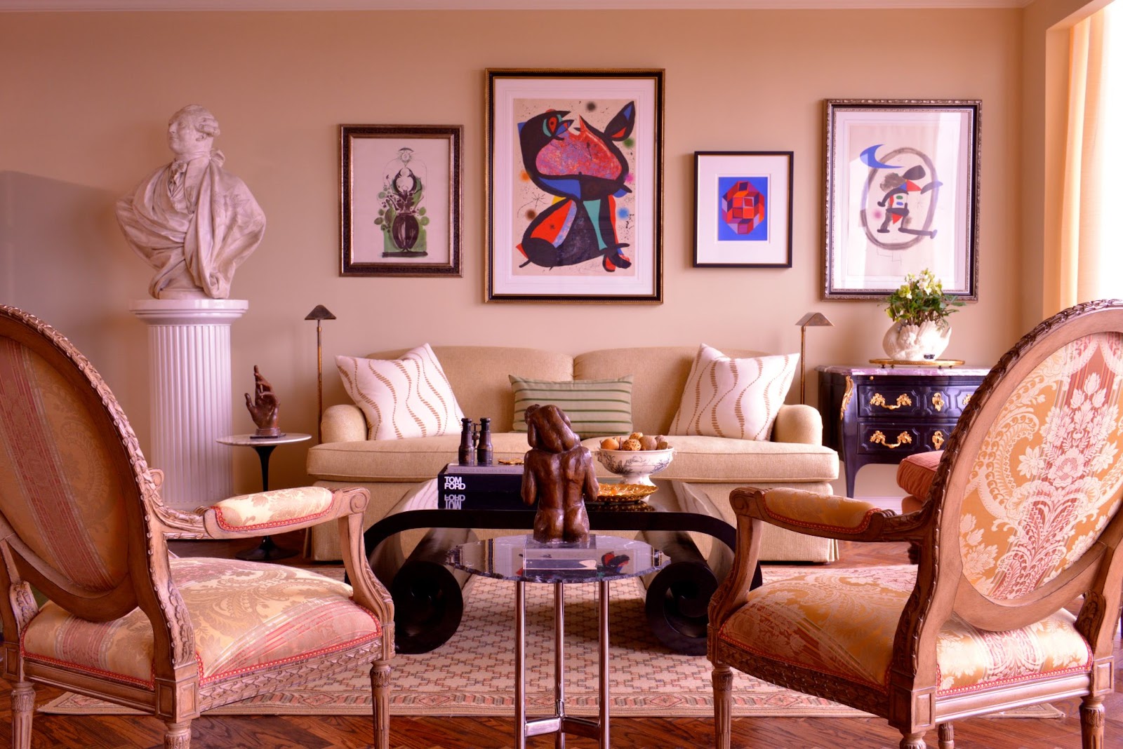 A designed living room space with neutral creamy-toned furniture offset with bold, colorful works of art on the wall.