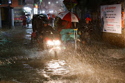 People ride rickshaws and motorcycle on a flooded street, amid continuous rain before the Cyclone Sitrang hits the country in Dhaka, Bangladesh, October 24, 2022. 