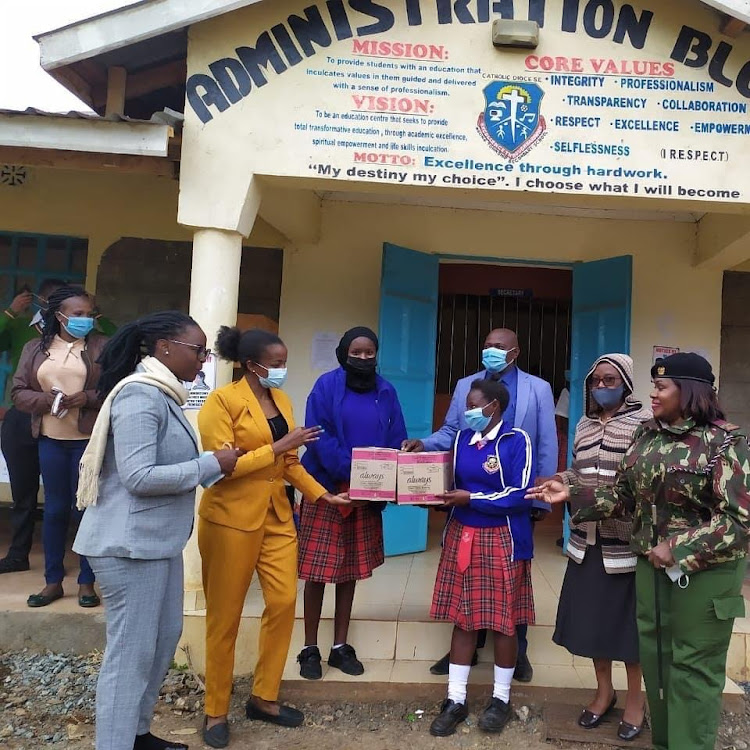 Jackline Saleiyan (in yellow suit) and other stakeholders, give sanitary pads to schoolgirls.