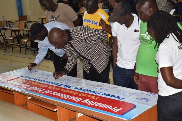 Youths sign a peace pledge during a leadership dialogue in Kisumu.