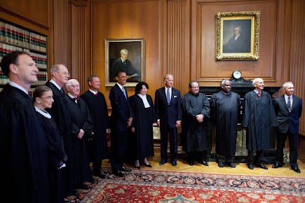 In this photo, the members of the Supreme Court (in their traditional black robes), stand with President Barack Obama, and then Vice-President (now President) Joseph Biden.