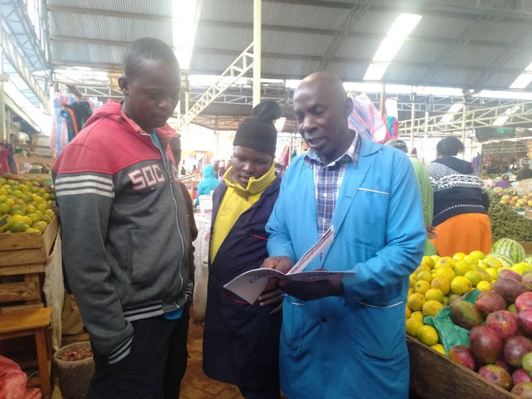 Nyeri open air market traders go through one of the BBI reports translated in Kiswahili at the market on Monday