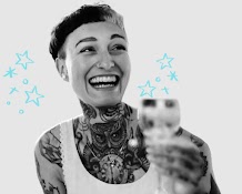 A smiling young tattooed woman holding a beverage