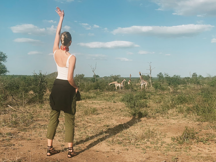 "Found my tribe." Leggy model Karlie Kloss greets giraffe in the South African bush.