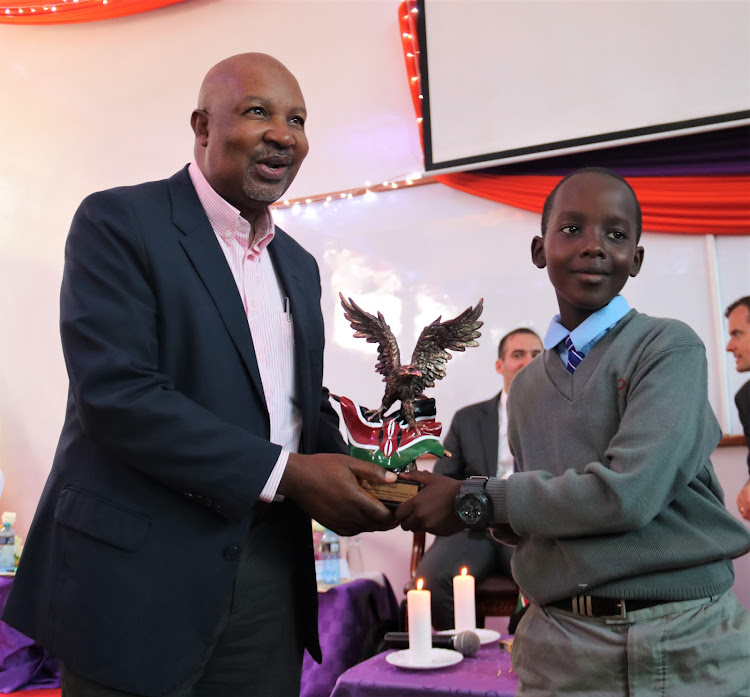 UN Information Centre deputy director Newton Kanhema receives a present from Ryan Mwirigi