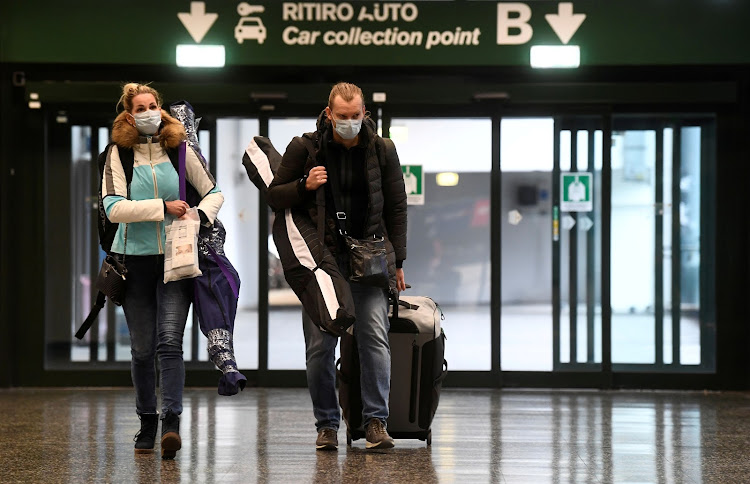 People wearing protective masks walk in Malpensa airport near Milan, Italy, March 9, 2020. An analysis released late on Thursday said samples taken in Milan and Turin on Dec. 18 showed the presence of the SARS-Cov-2 virus.