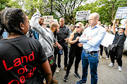 STAND-OFF: Black First Land First members clash with #saveasouthafrica  members outside the Gupta compound in Saxonwold, Johannesburg. BLF members argued that white people should not  attack the family 'because  white people  own most of the companies on the JSE'. The group  held up signs saying '#HandsOffZuma'Picture: MOELETSI MABE