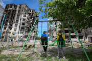 Teenagers Oleskandr and Bohdan sit on swings in front of residential buildings destroyed during Russia's invasion of Ukraine in the town of Borodianka, in Kyiv region, Ukraine May 13, 2022.  